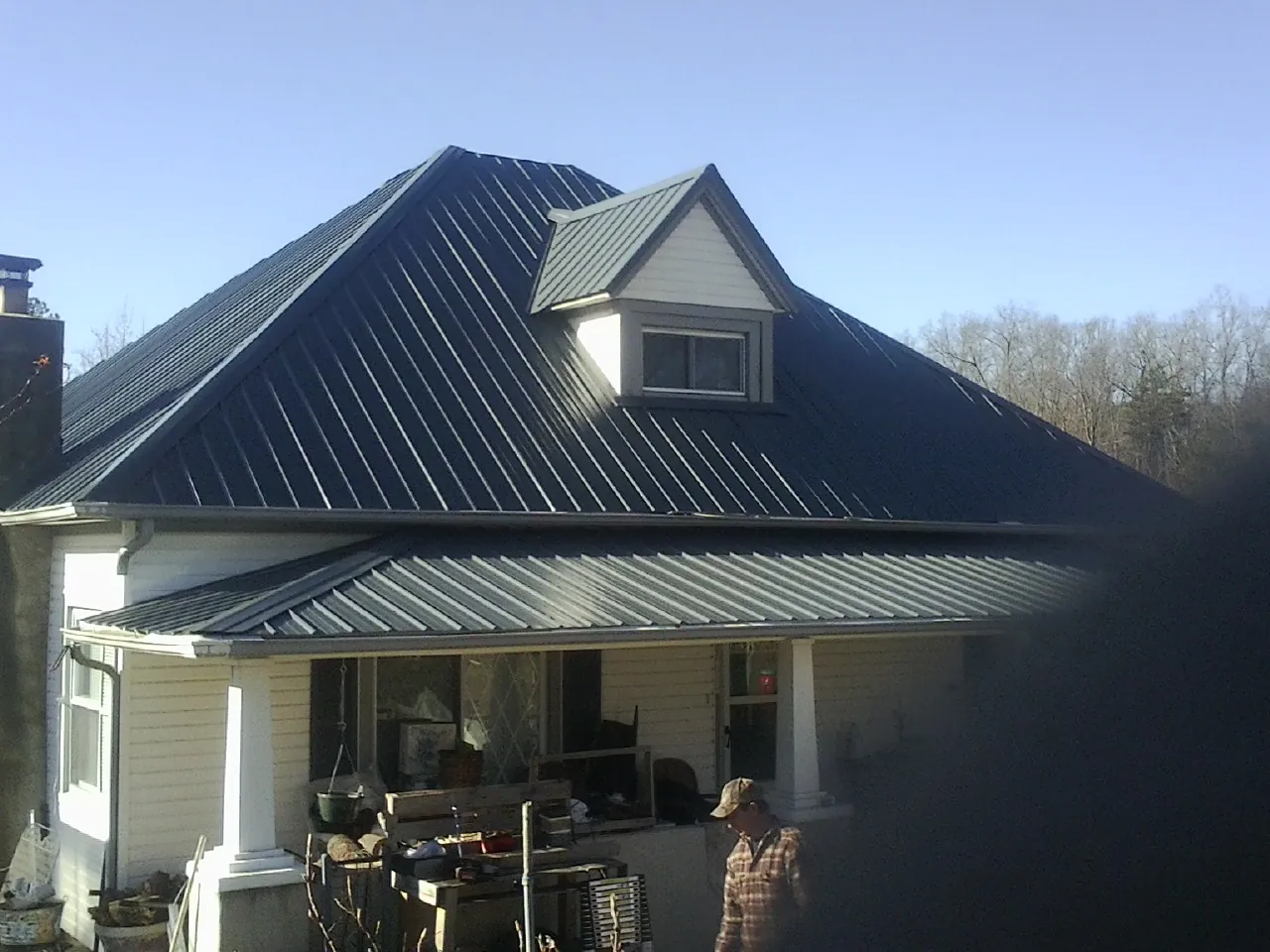 Dark blue standing seam metal roof with a dormer above a front porch in Hopkins